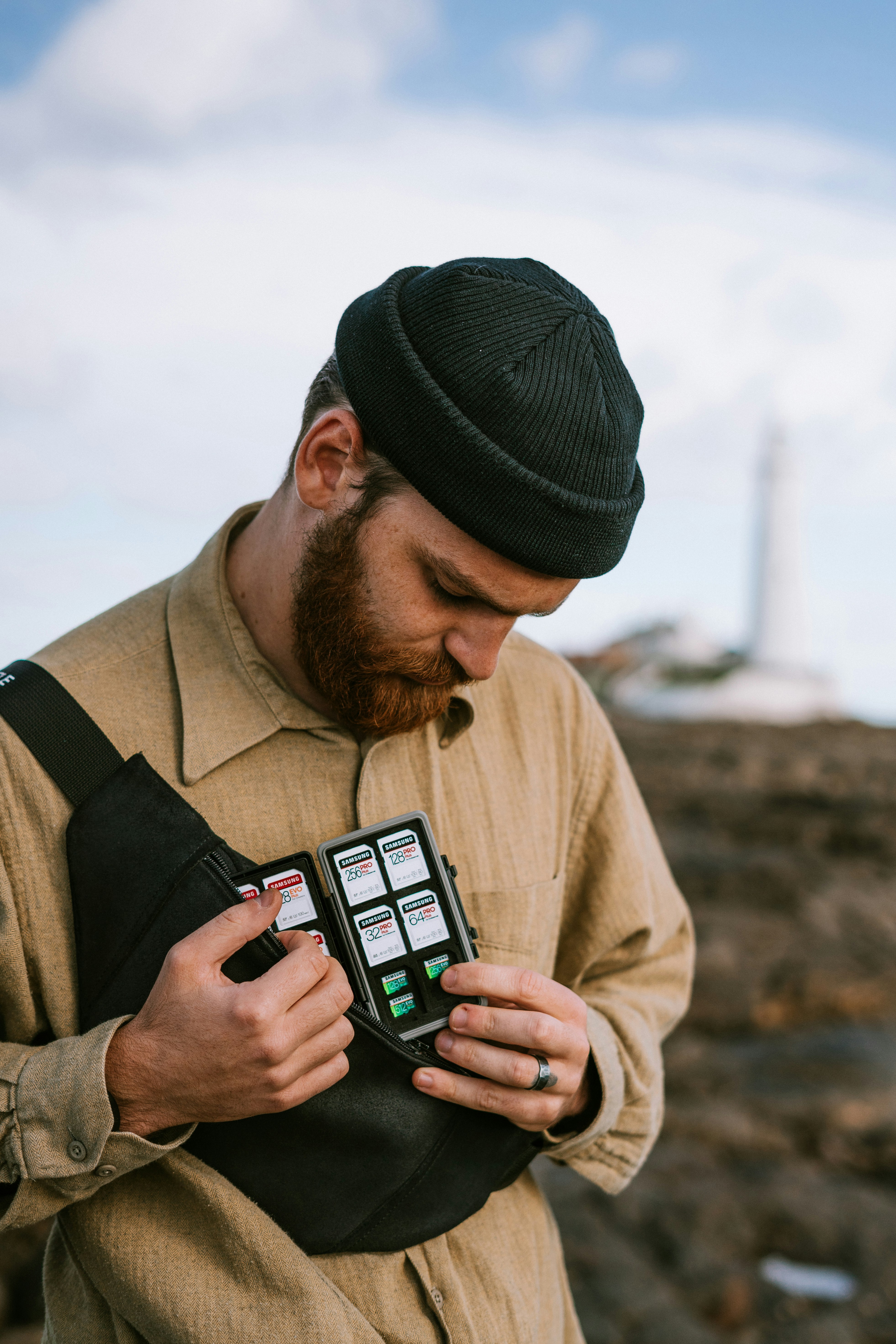 man in brown jacket holding black smartphone