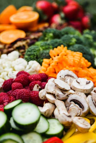 Fresh broccoli, cauliflower, raspberries, sliced mushrooms, and cucumbers arranged for a healthy meal