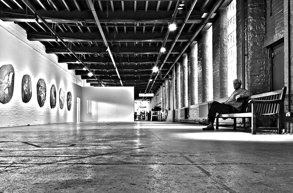 grayscale photo of man sitting on chair