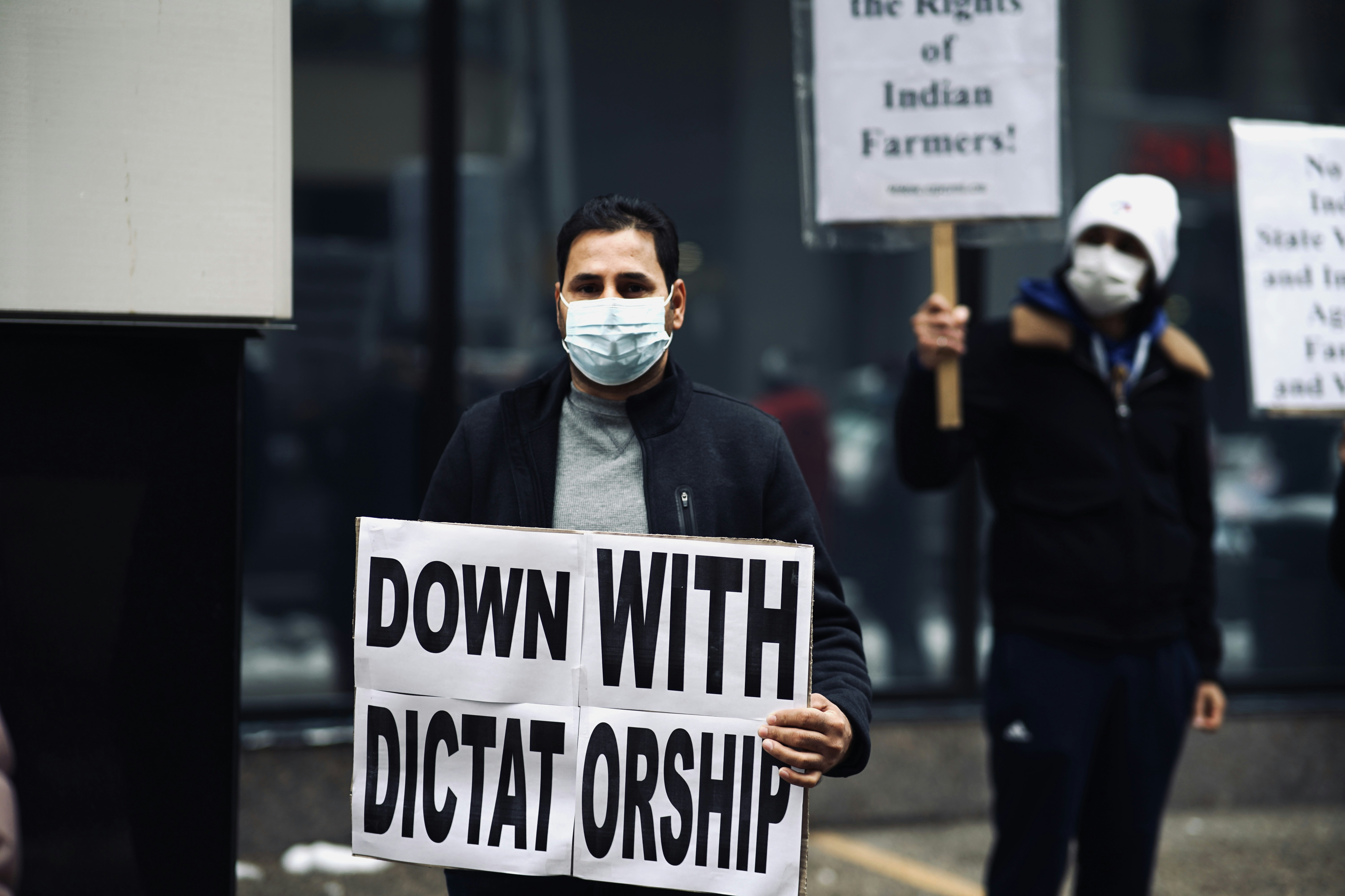 man in black jacket holding white and black no smoking sign