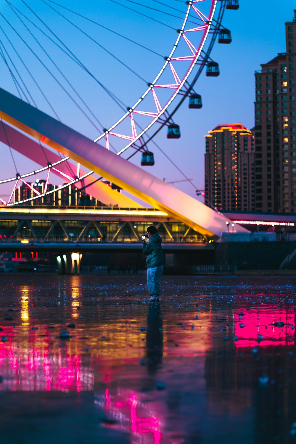 man in blue denim jeans standing on bridge during night time