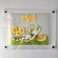 A framed artwork features a vibrant sneaker with intricate designs and patterns, surrounded by cartoonish yellow flowers with black centers. The word 'DASH' is prominently displayed above the sneaker in bold, yellow lettering. The background is a simple grassy green, creating a lively and playful composition.