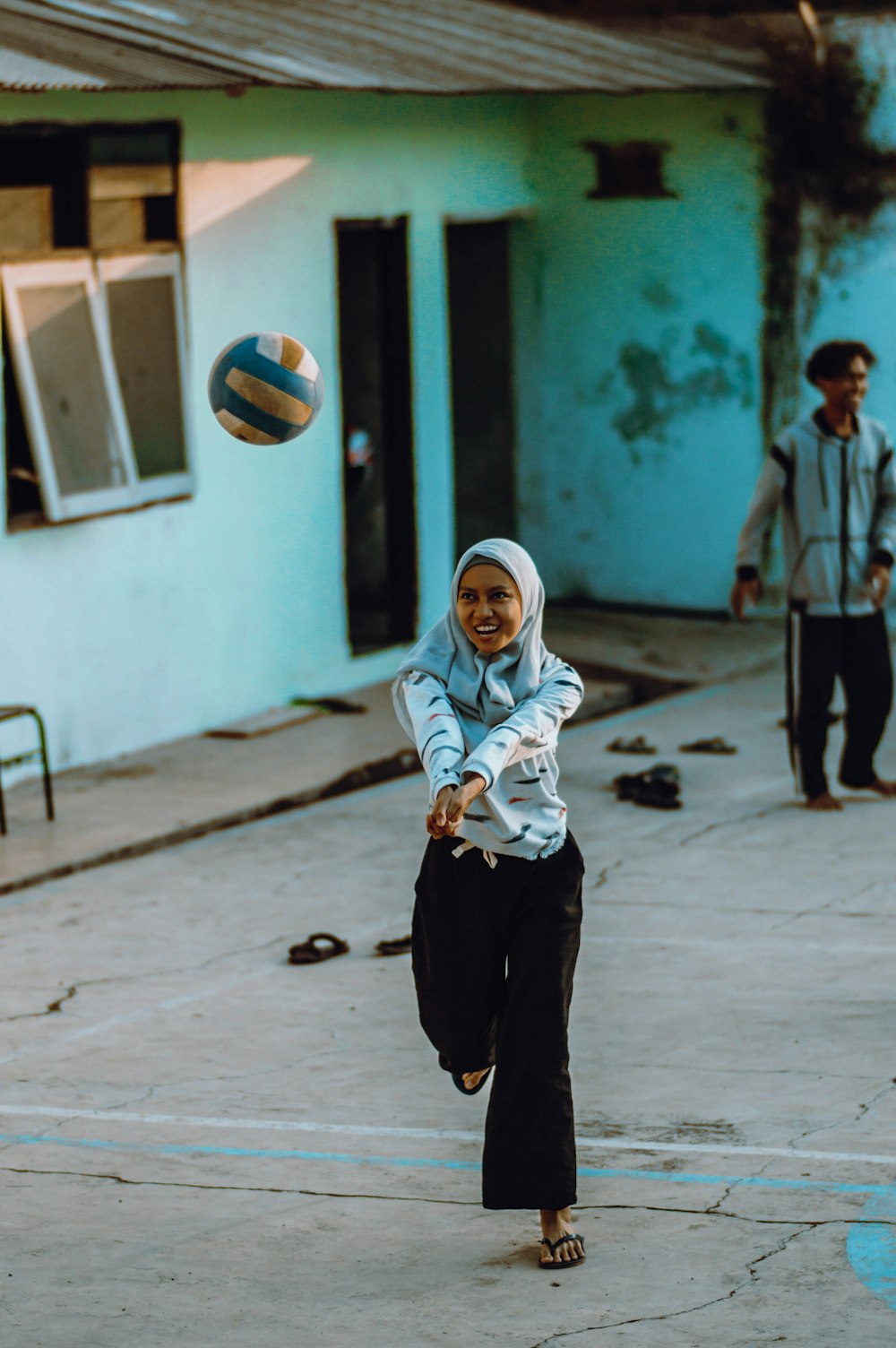 Mujer con hiyab blanco y pantalones negros de pie sobre suelo de hormigón gris