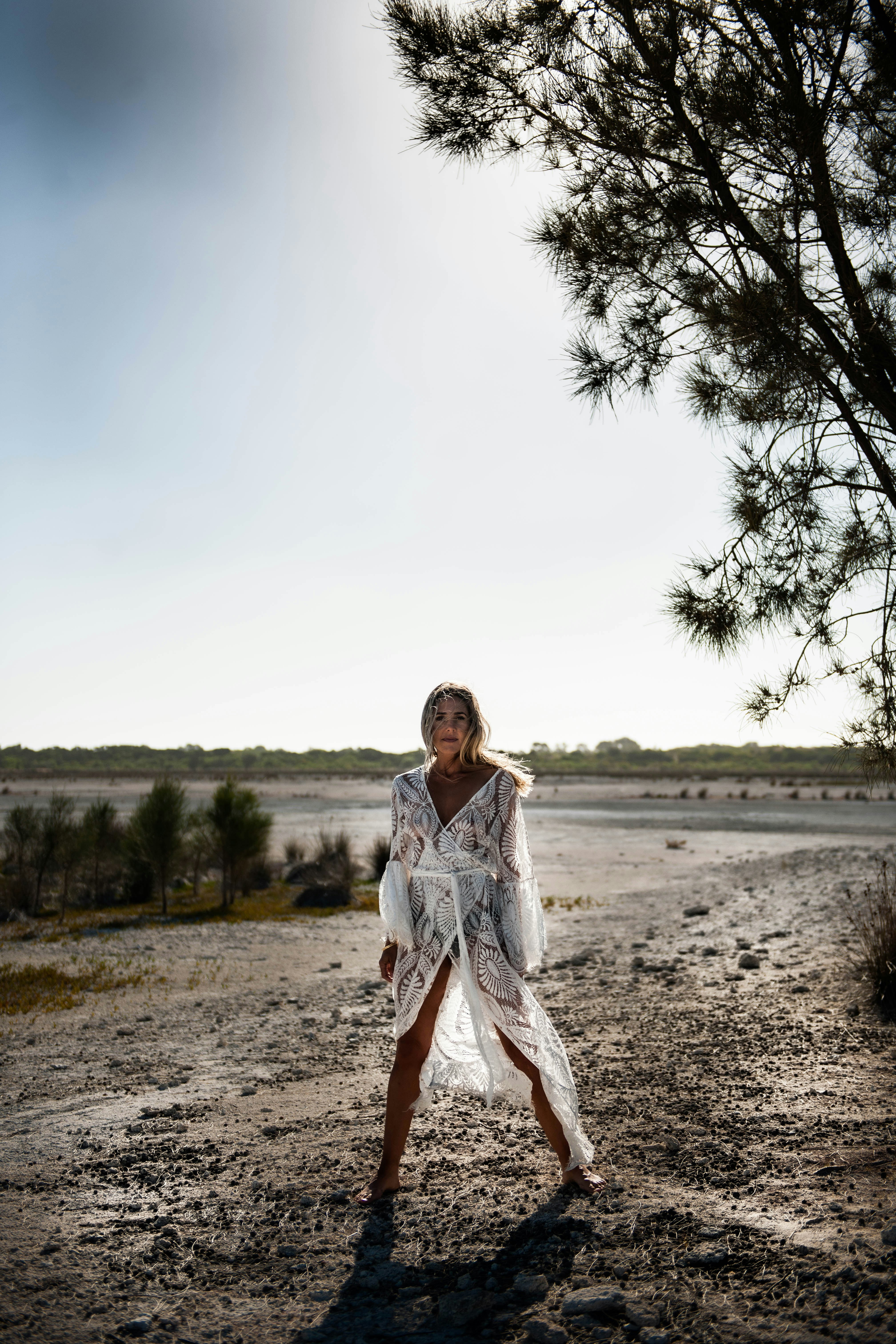 woman in white long sleeve dress standing on brown field during daytime