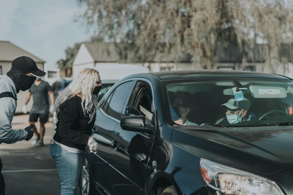 woman in black jacket standing beside black suv during daytime