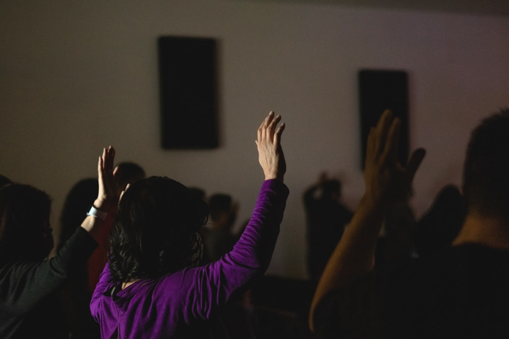 woman in purple long sleeve shirt raising her hands