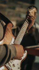 person playing brown and white electric guitar