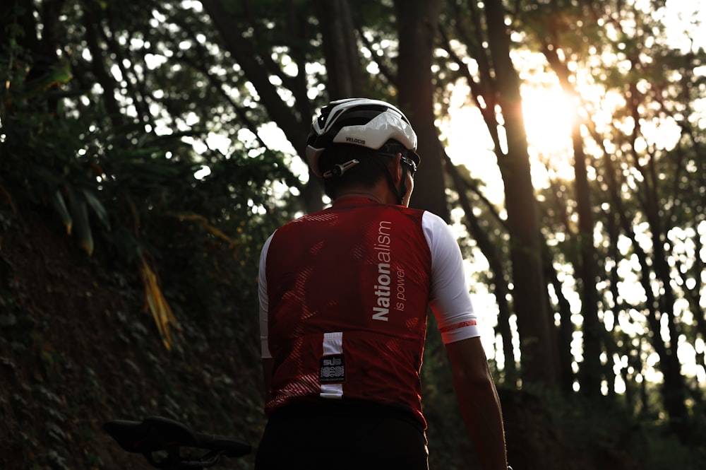 man in red and white long sleeve shirt wearing black helmet standing on rocky hill during