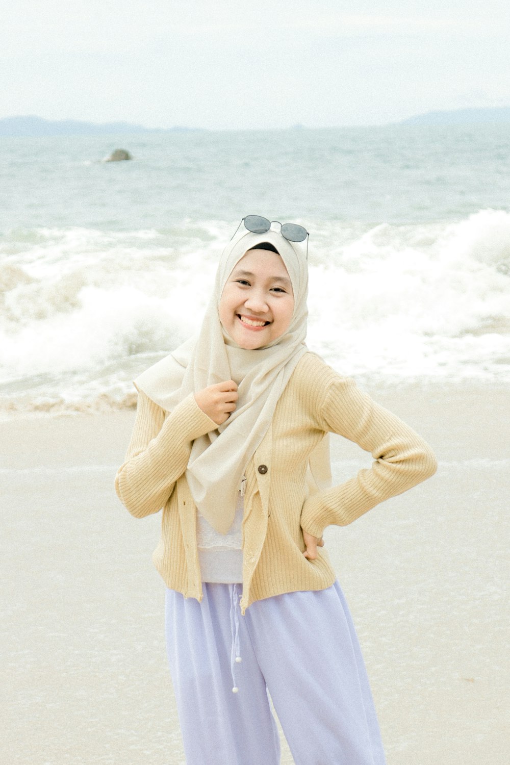 woman in white hijab and white long sleeve shirt standing on beach during daytime