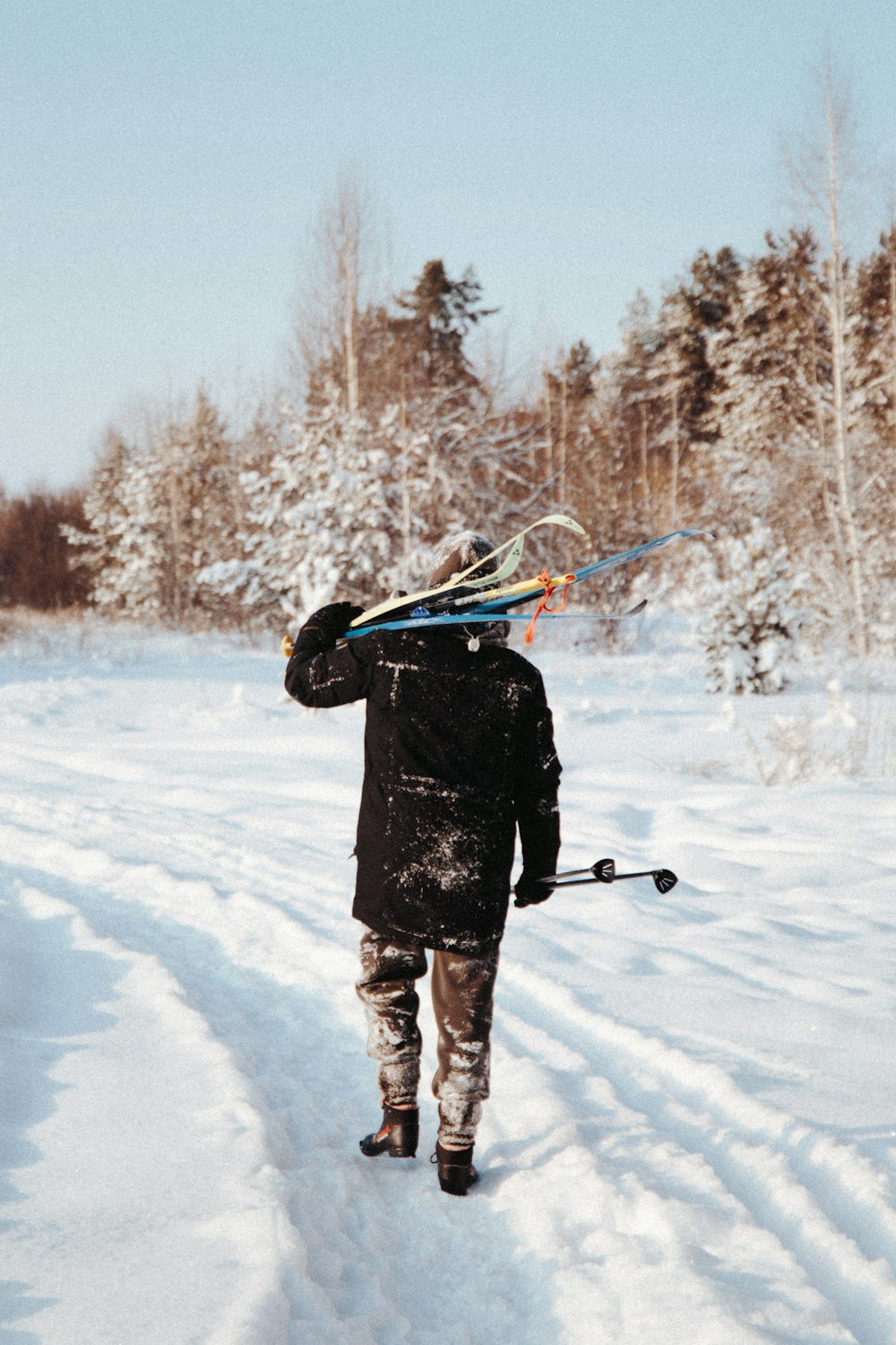 person in black jacket and brown pants holding ski pole on snow covered ground during daytime