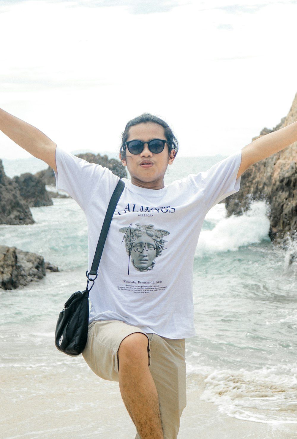 woman in white crew neck t-shirt and black shorts sitting on beach shore during daytime