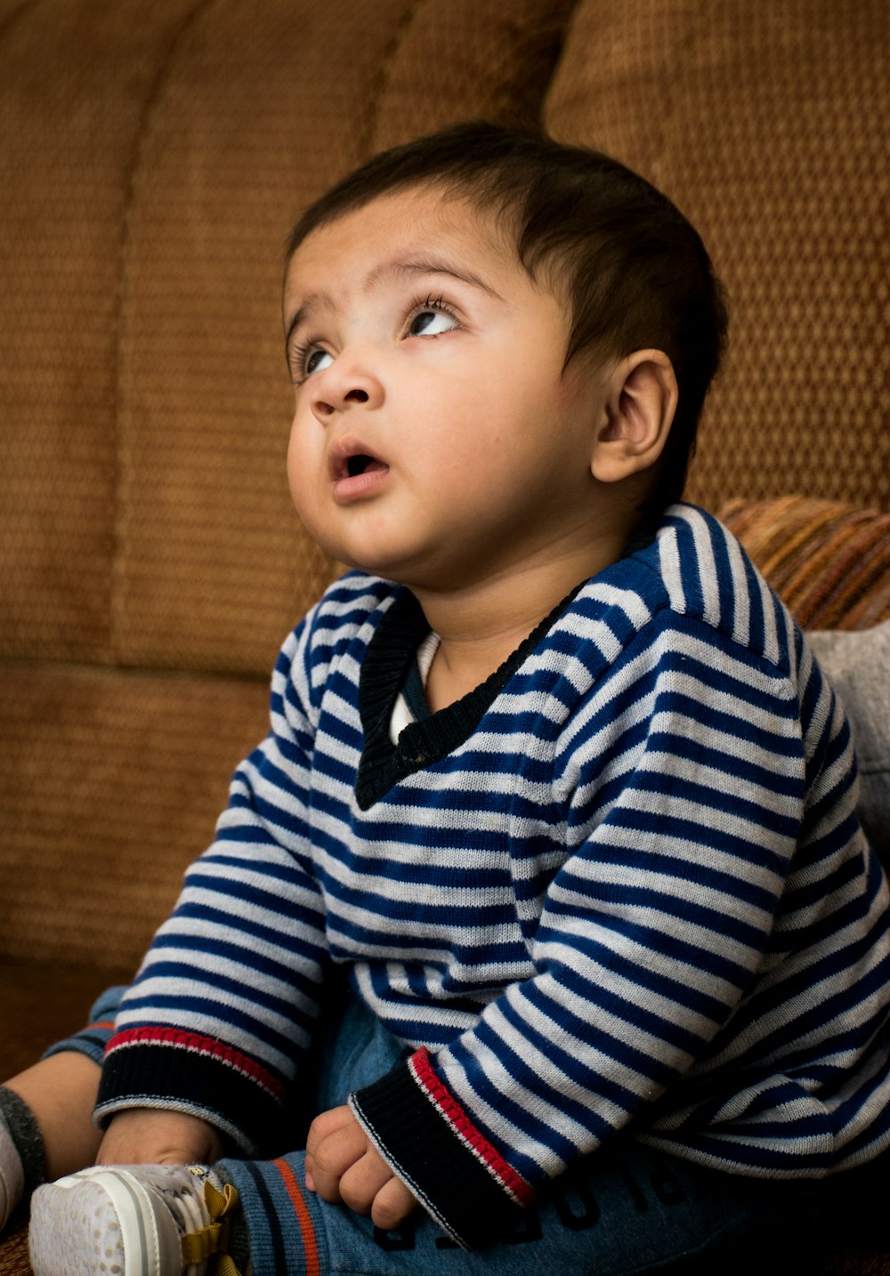 boy in blue and white striped long sleeve shirt sitting on brown sofa
