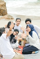 A group of friends enjoying a picnic on the beach with colorful blankets.