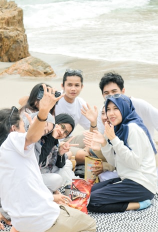 A group laughing and sharing snacks on the beach after a volleyball game.