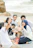 Group of friends enjoying ceviche on the beach with fishing gear and ocean waves behind them.