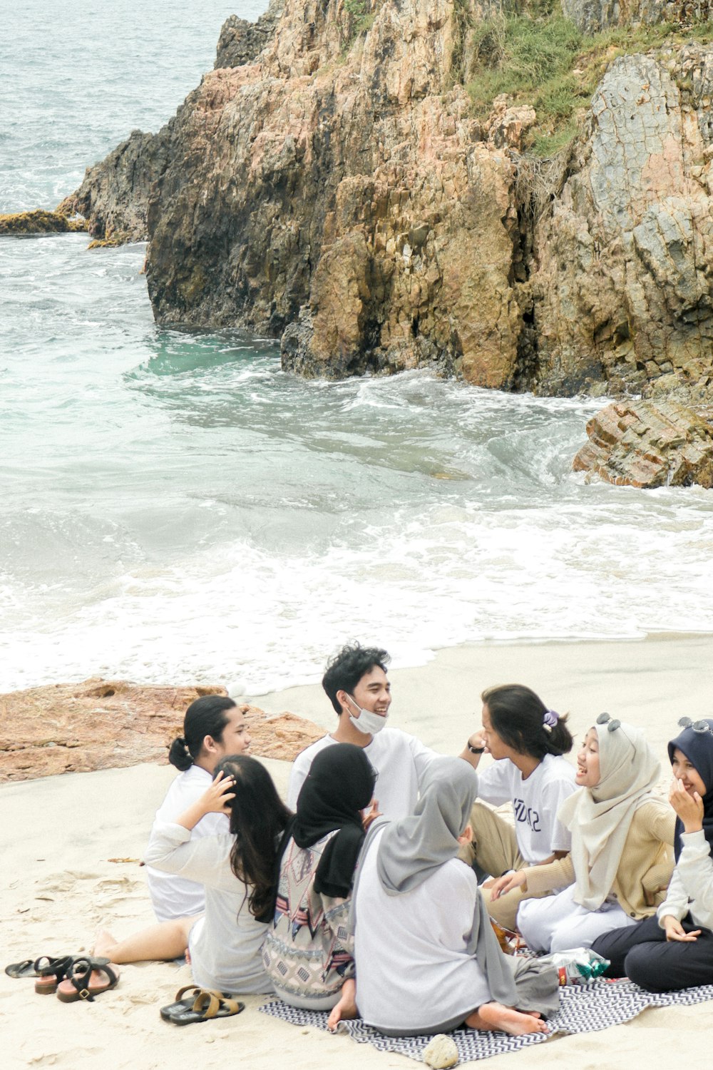 people sitting on brown sand near body of water during daytime