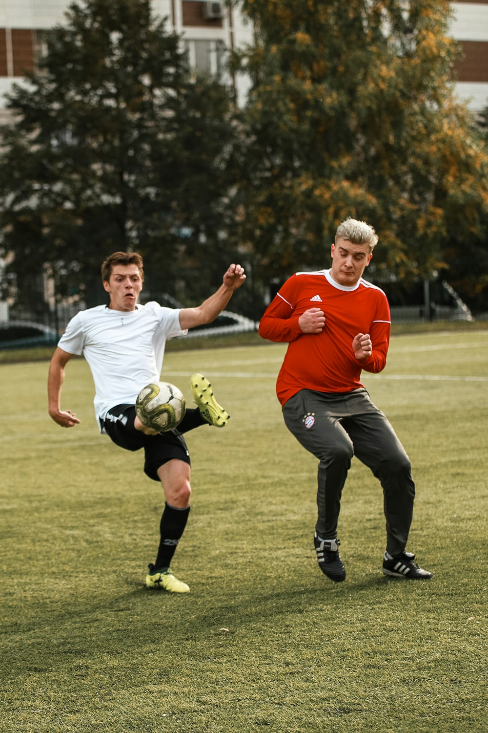 2 men in red shirt playing soccer during daytime