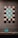 A display of intricately designed tiles with geometric and floral patterns. The tiles are arranged in a symmetrical pattern on a wall, featuring a blend of turquoise and earthy tones. A leaf-shaped ceramic ornament sits on a stand below, matching the tiles' color scheme.