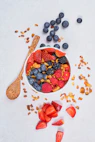 red strawberries and blue berries on white ceramic bowl