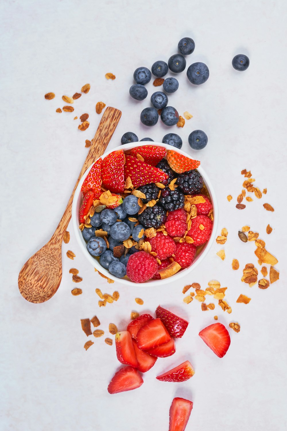 red strawberries and blue berries on white ceramic bowl