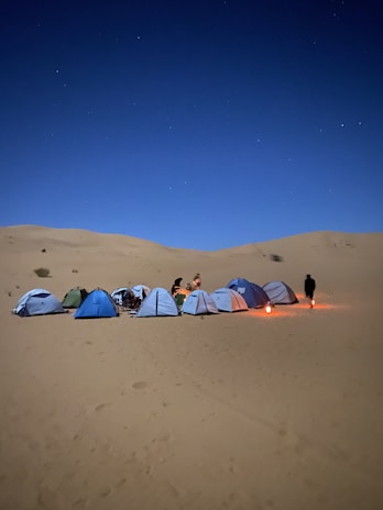A group of travelers setting up tents under a starry desert sky in Egypt.