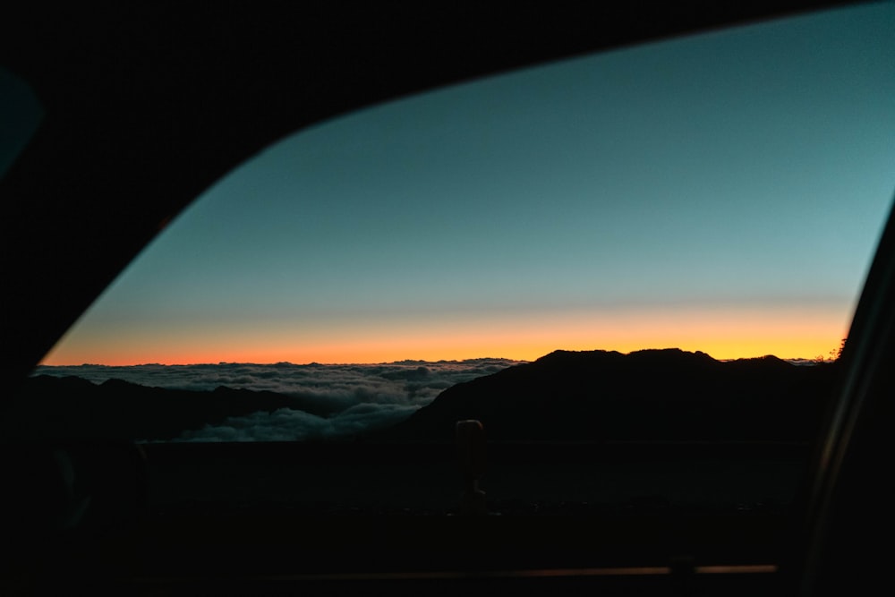 silhouette of person standing on hill during sunset