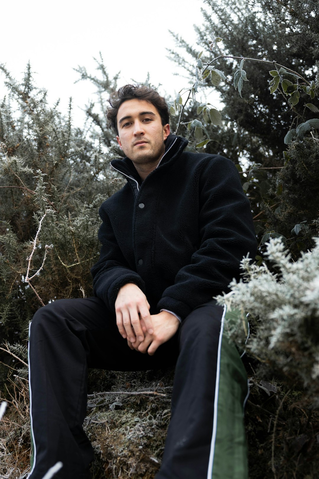 man in black zip up jacket sitting on tree