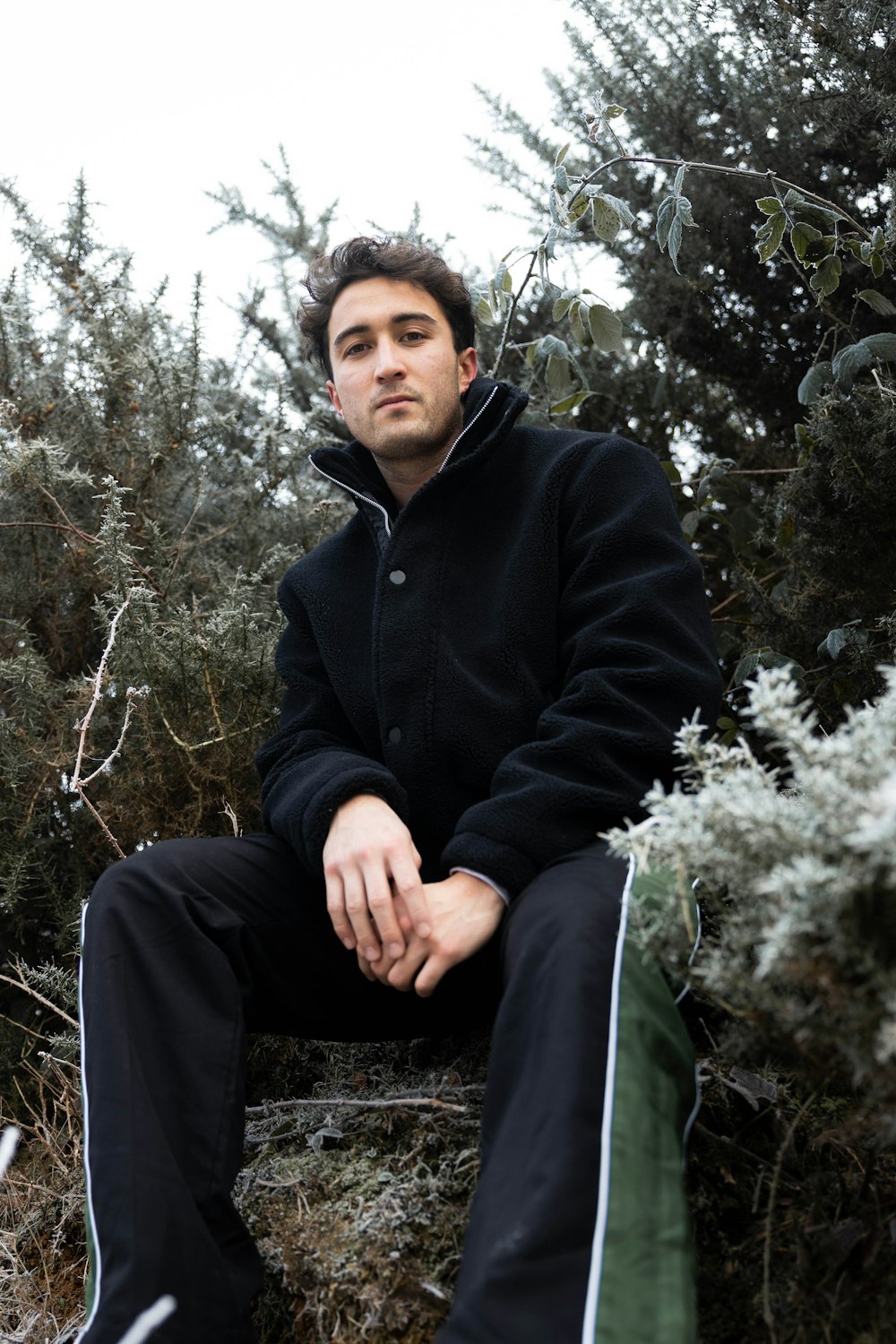 homme en noir veste zippée assis sur un arbre