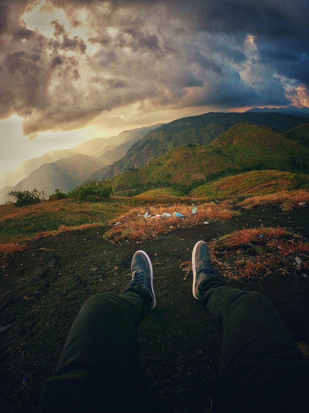 person in black pants and white sneakers sitting on brown grass field during daytime