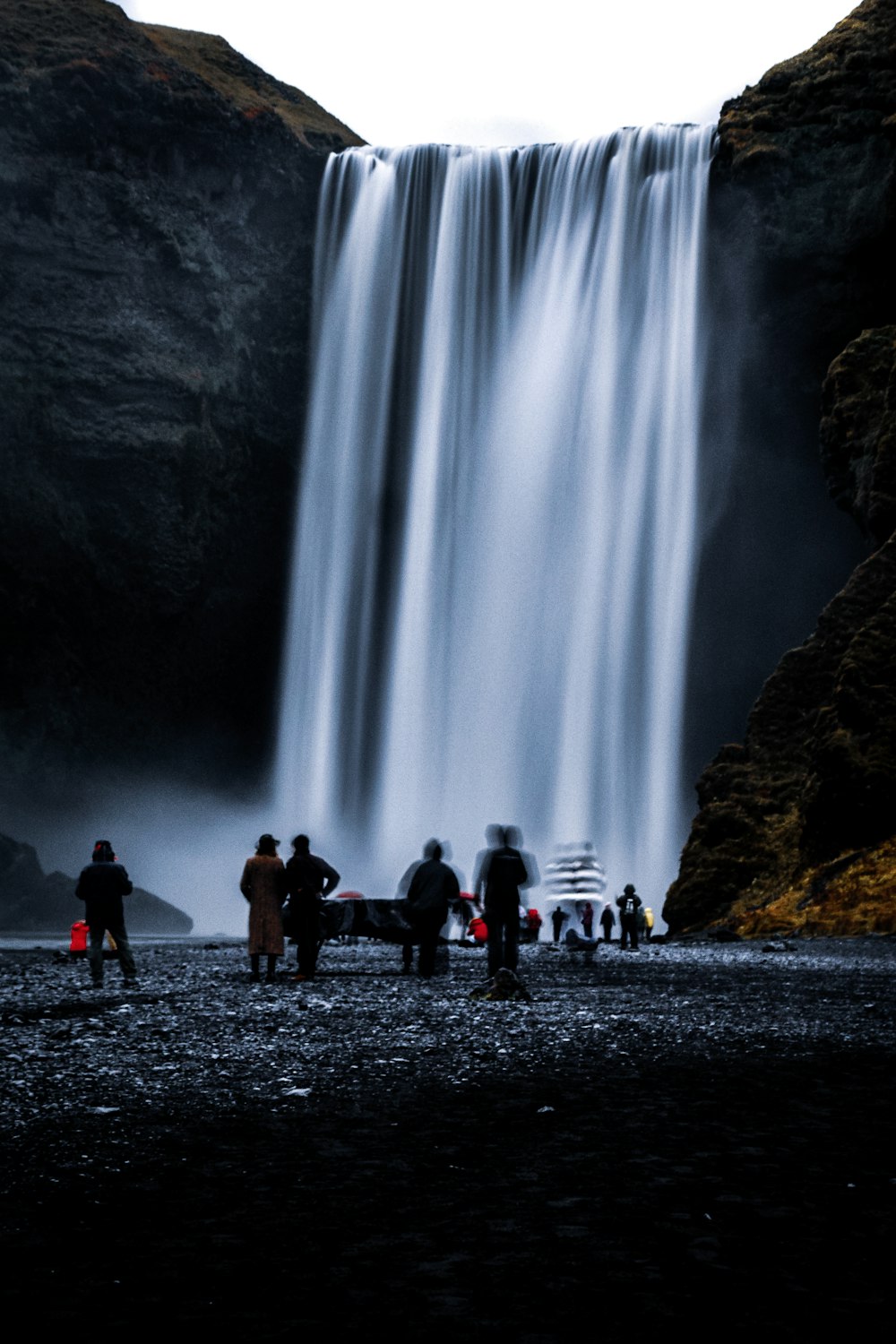 personnes debout près des chutes d’eau pendant la journée