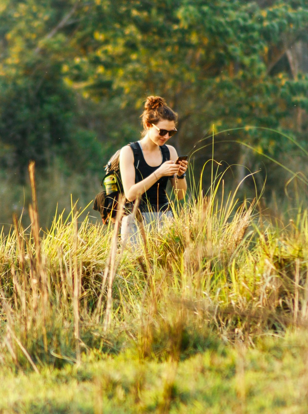 woman in black tank top and black shorts sitting on brown grass during daytime