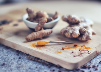 Close-up of vibrant Korean turmeric root and green plant extracts on a wooden table.