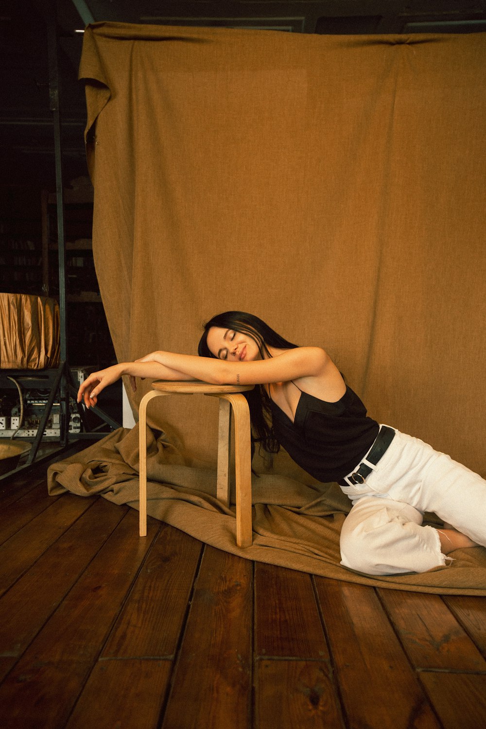 woman in black tank top and white pants sitting on brown wooden chair