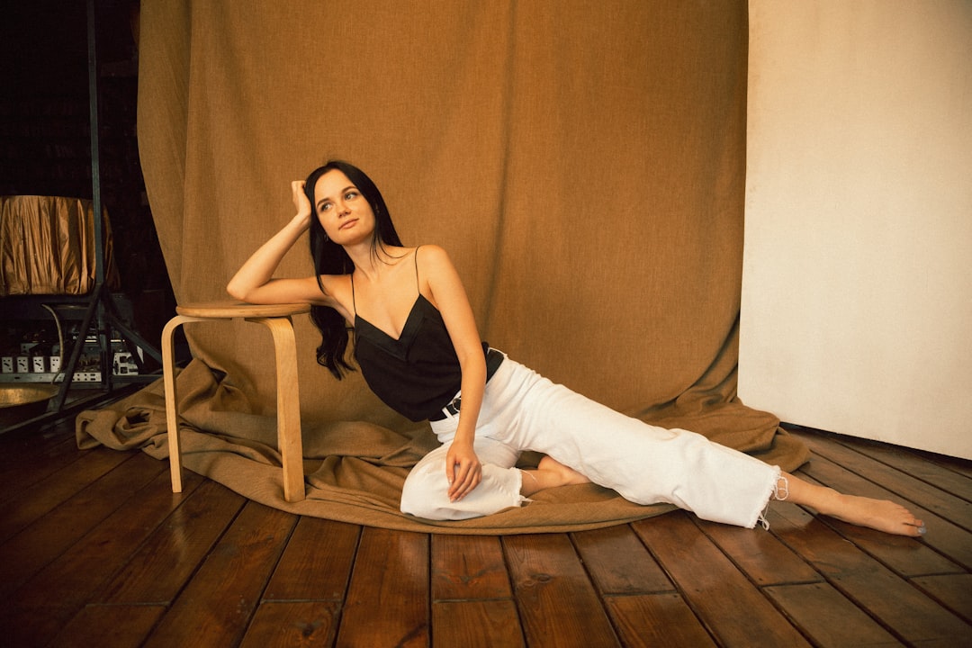 woman in black spaghetti strap top and white pants sitting on brown wooden chair