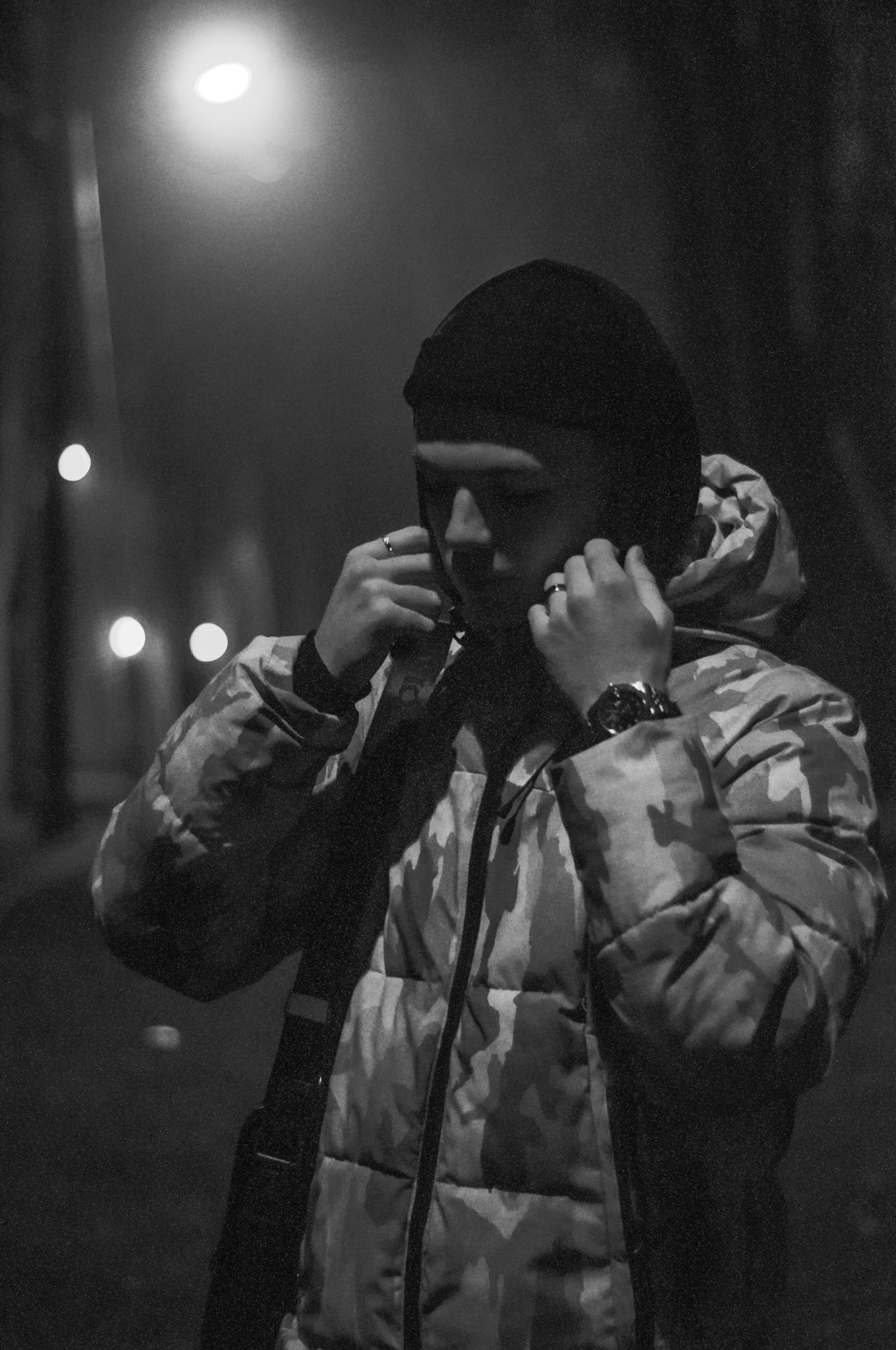 man in black knit cap covering his face with his hand