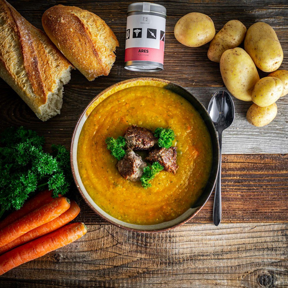 carrots and meat on blue ceramic bowl beside brown bread