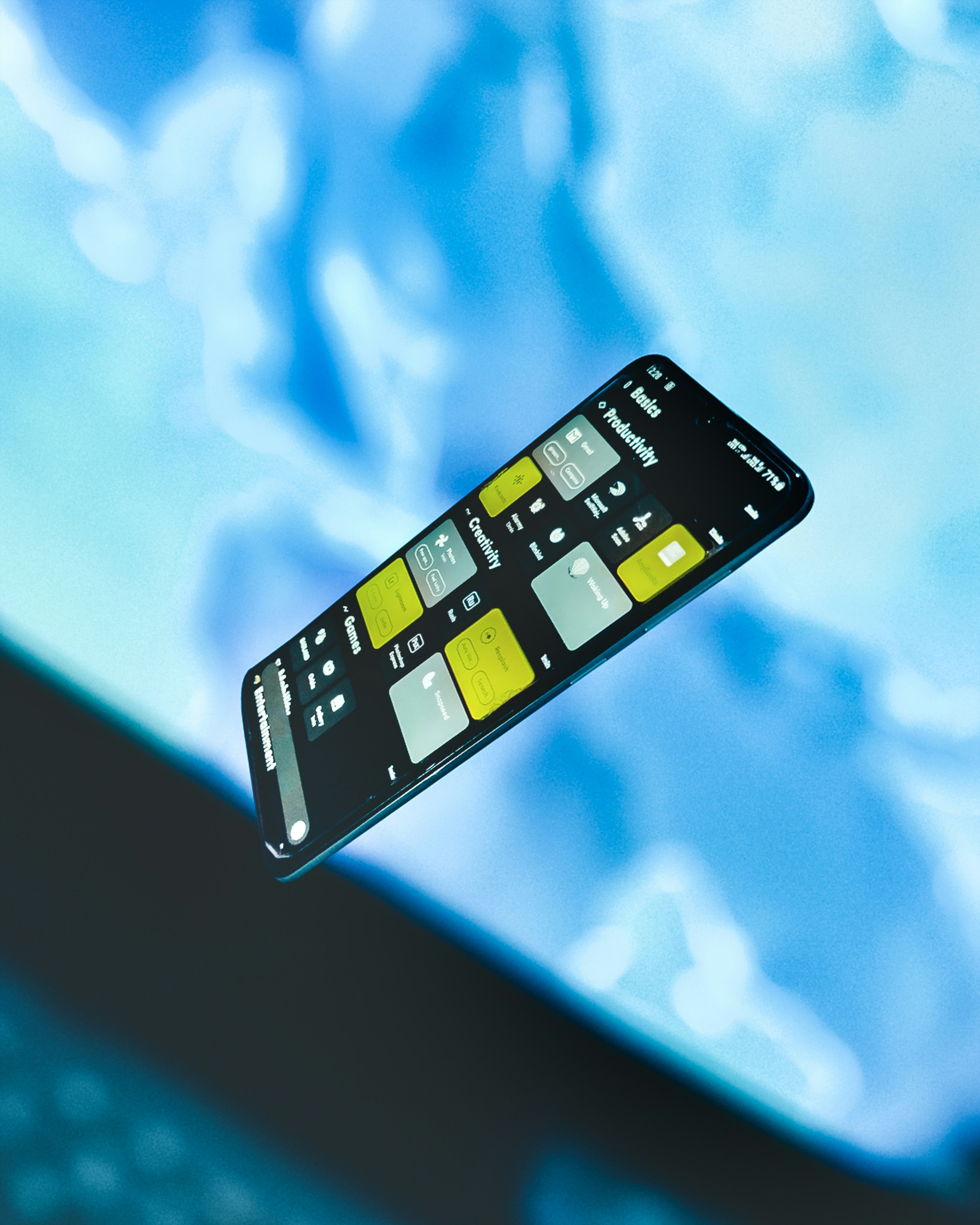 Black smartphone displaying app categories on a blue background.