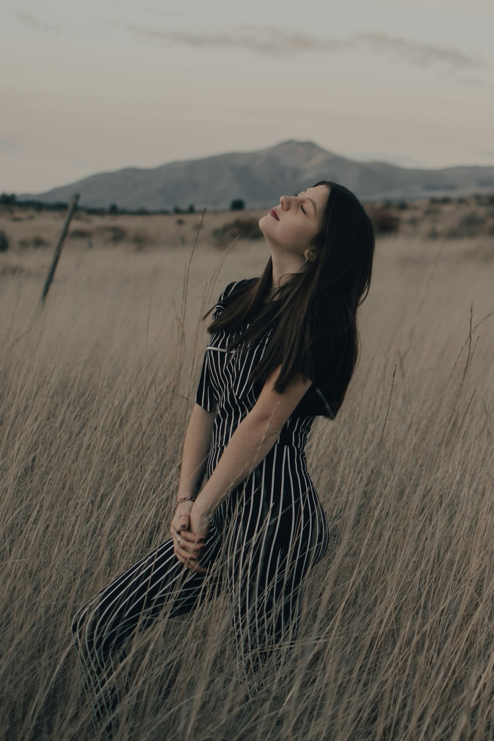 woman in black and white stripe dress standing on brown grass field during daytime