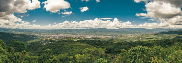 A panoramic view of lush green valley stretching beneath the clear blue sky at Sri Ramaa Resorts.