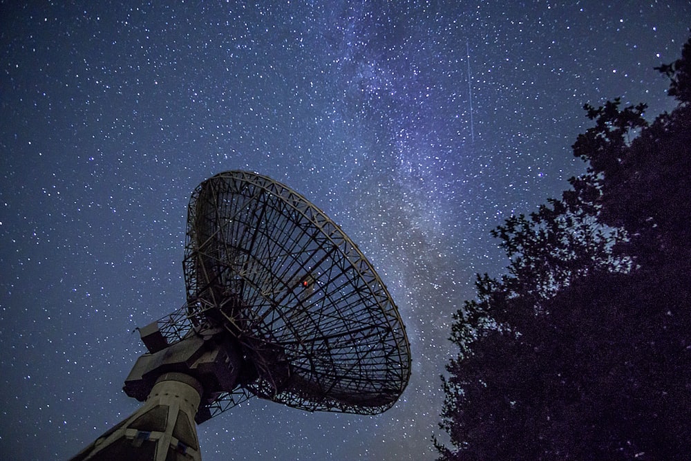 Antena parabólica blanca bajo el cielo azul durante la noche