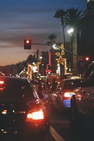 A modern city street at dusk with glowing neon lights and bustling people.