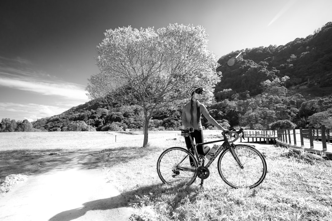 grayscale photo of man riding bicycle on beach