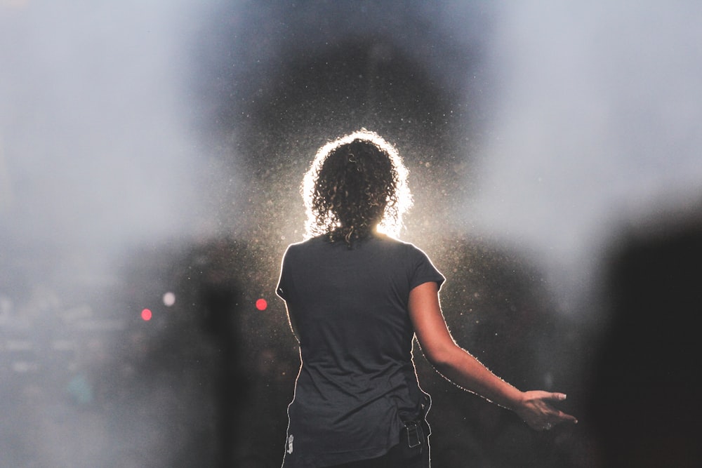 man in black t-shirt standing and raising his hands