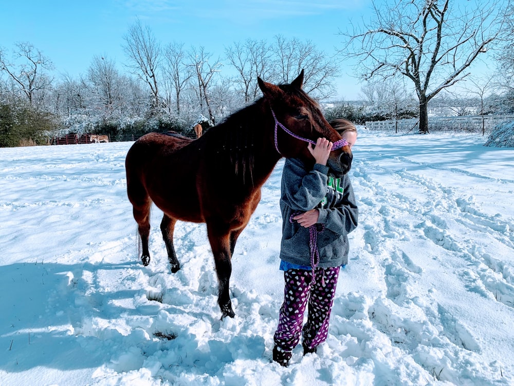 woman in white and black polka dot dress standing beside brown horse during daytime