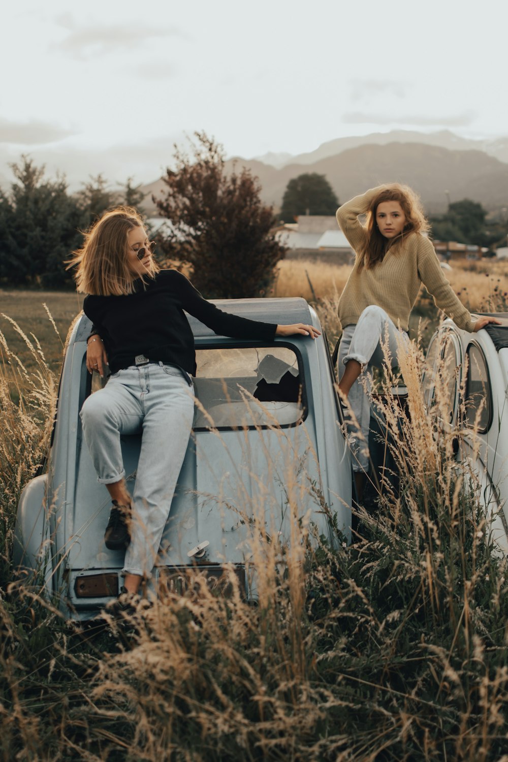 woman in black shirt and white pants sitting on white car