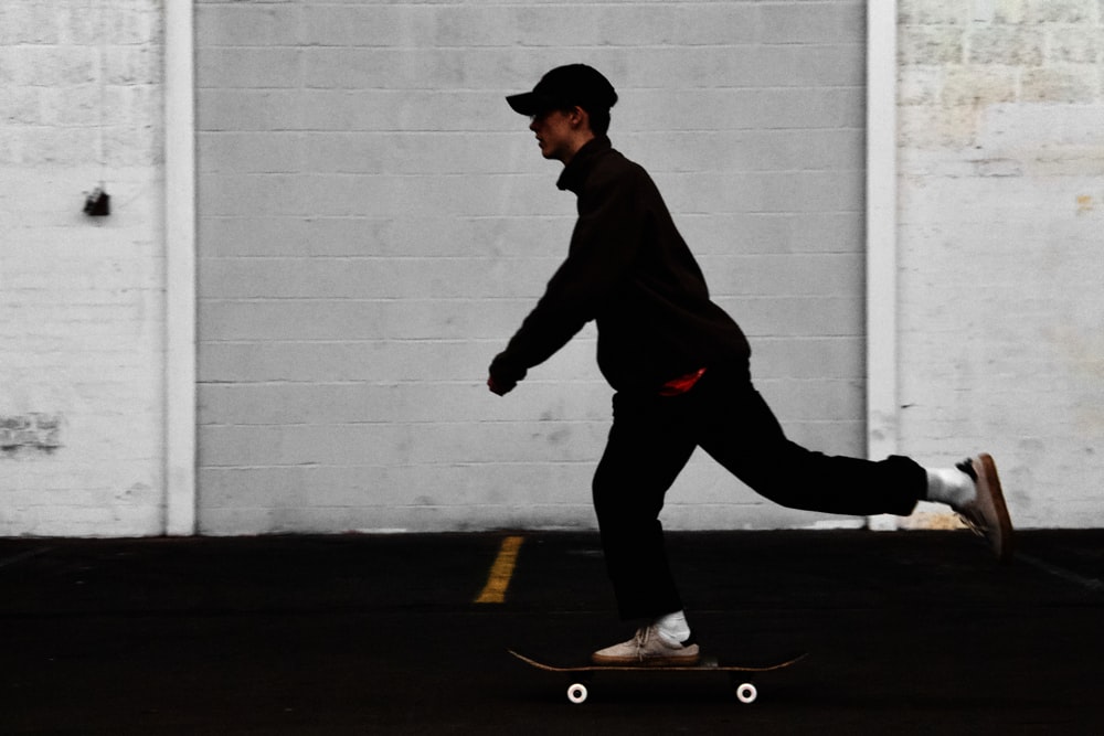 黒いズボンと茶色のジャケットを着た男がスケートボードに乗っている