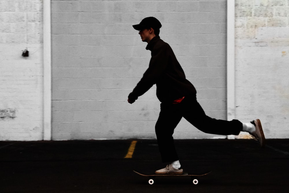 homme en pantalon noir et veste marron équitation planche à roulettes