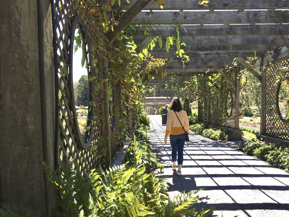 woman in brown shirt and black pants walking on pathway