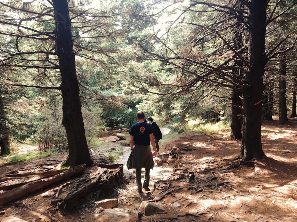 man in black t-shirt and black shorts walking on forest during daytime