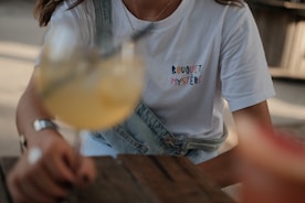 woman in white crew neck t-shirt holding clear drinking glass